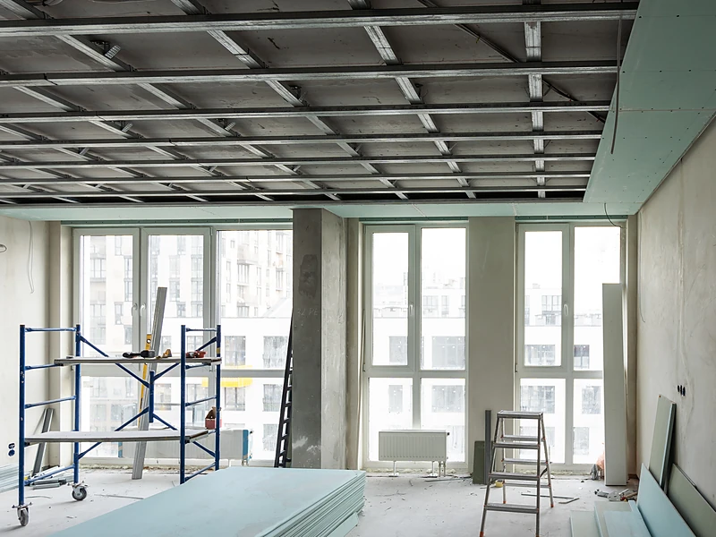Commercial floor under construction with scaffolding and drywall staged for a build-out